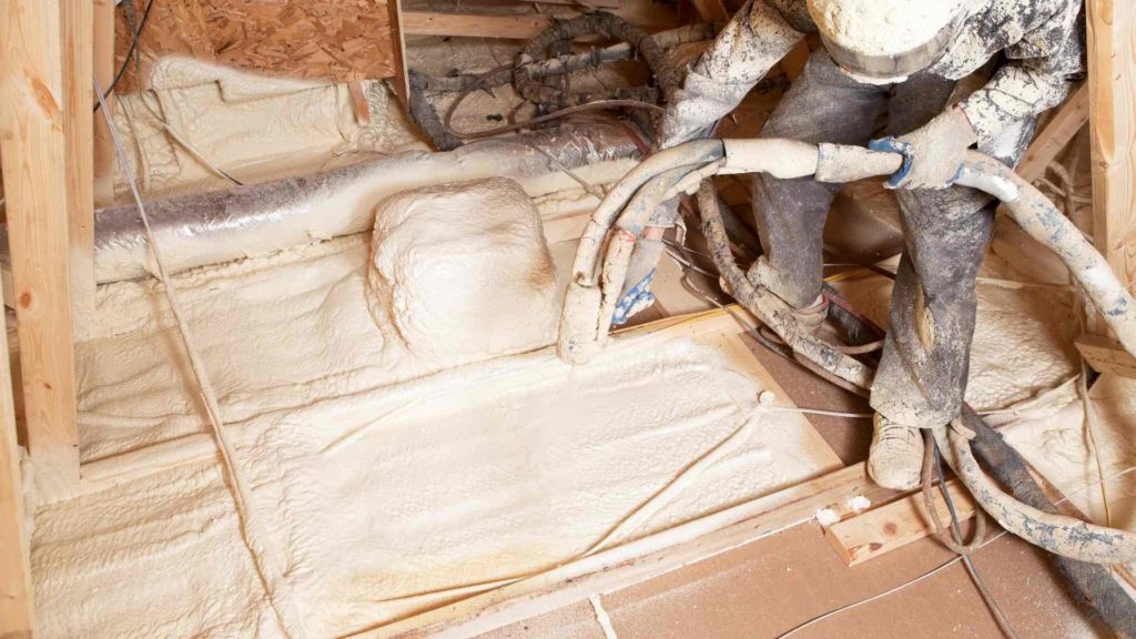 A man is applying residential spray foam insulation in a house.