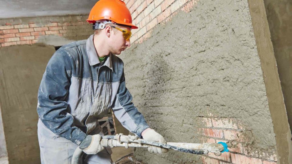 A construction worker using a concrete mixer for spray-on coatings.
