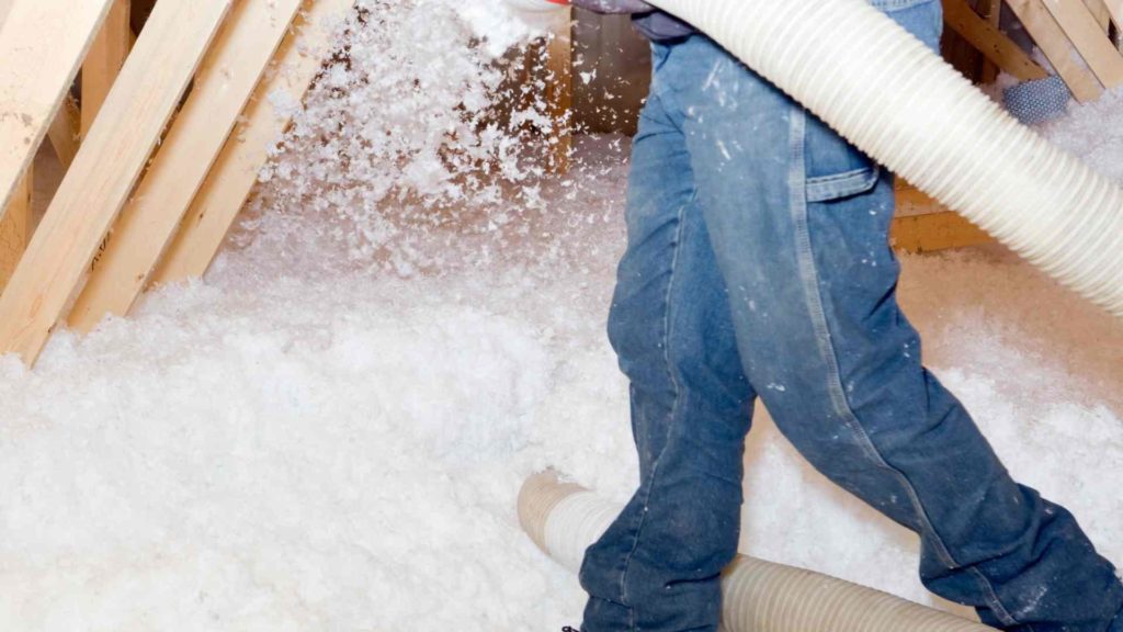 A man installing blown-in insulation in an attic.